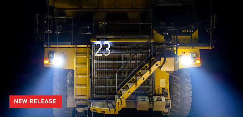 Large Mining Truck at night, with head lamps shining clearly on group