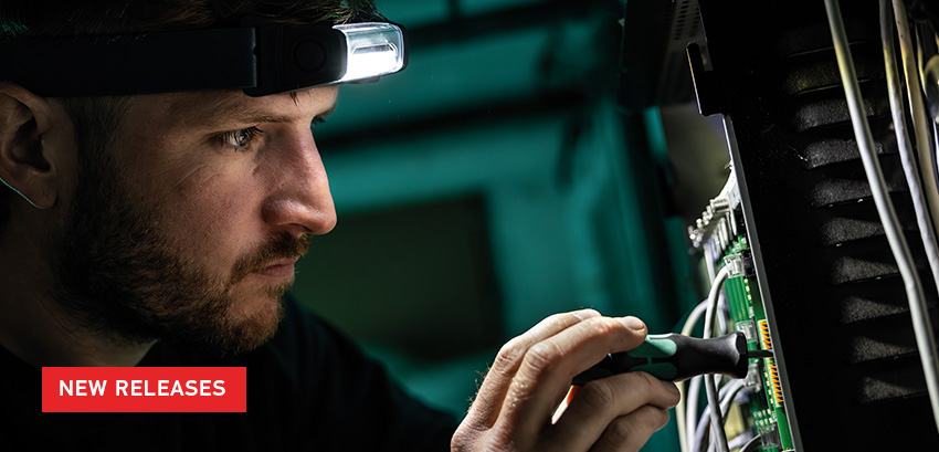 New Release text over image of male with headlamp working on circuit board